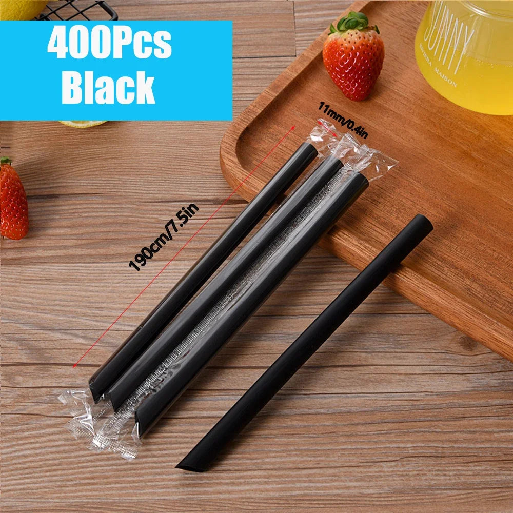 A set of 400 reusable black plastic drinking straws laid out on a wooden board with a strawberry and a glass of juice.