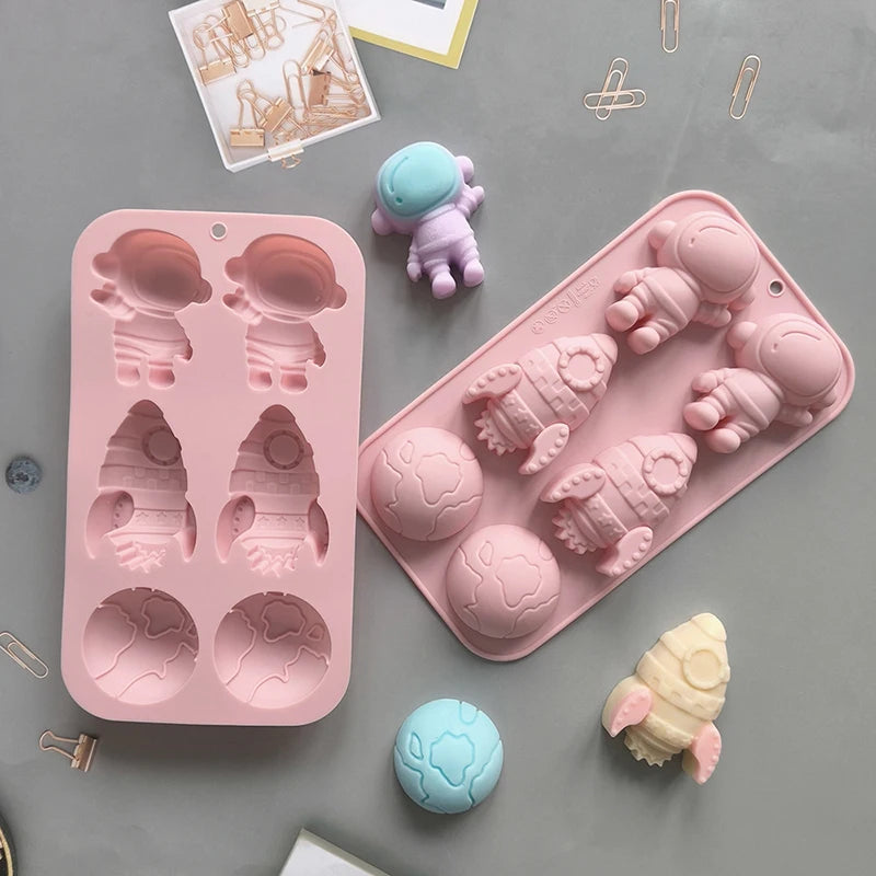 A pink silicone mold tray with various astronaut and space-themed shapes for DIY crafts