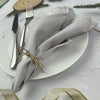 A set of reusable cotton cloth napkins folded and tied on a white plate with silverware.