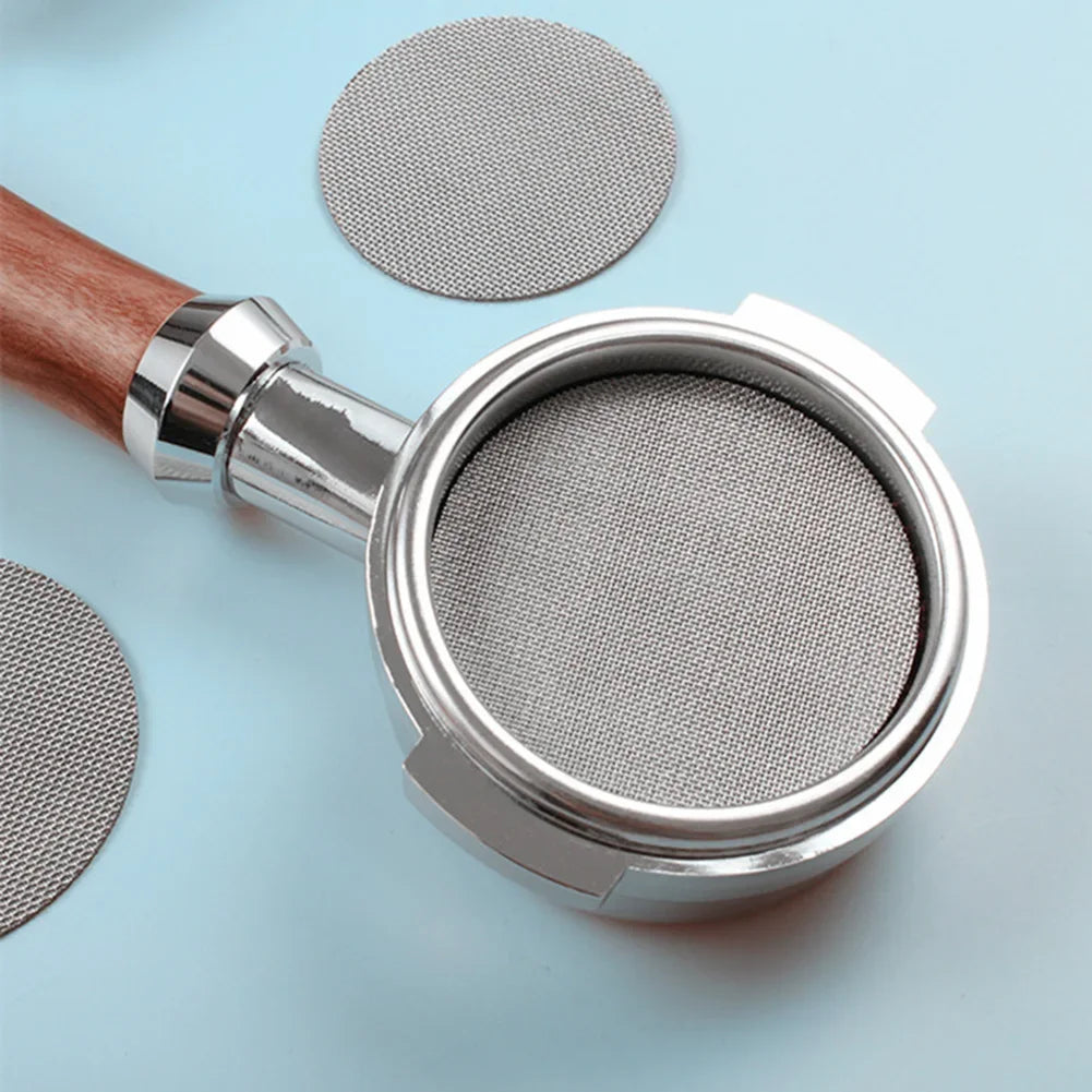 A silver precision coffee filter plate replacement is shown next to a wooden handle and two circular metal plates on a light 