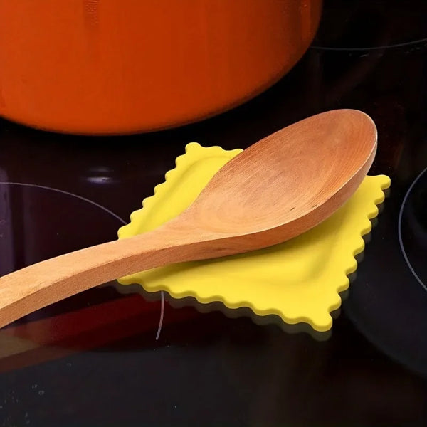Ein Holz-Keksschaufel-Ständer liegt auf einer gelben Silikonmatte neben einem orangen Topf.