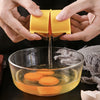 Hands are using a portable egg cracker to separate eggs in a glass bowl.