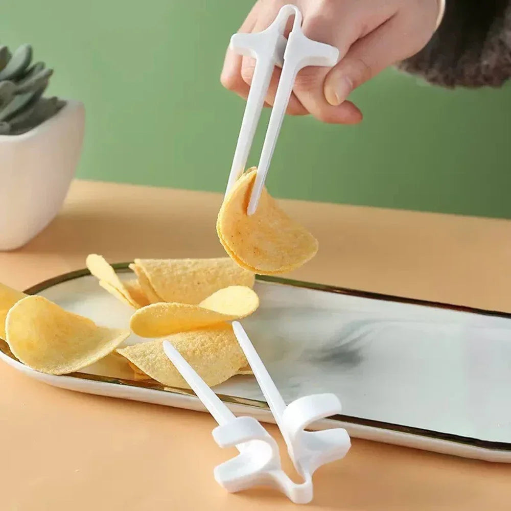 A hand is using white precision finger chopsticks to pick up and move thin, round crackers on a plate.