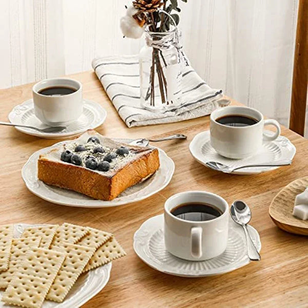 Ein Set von sechs Edelstahl-Espresso-Löffeln auf einem Holztisch mit Kaffeetassen und Gebäck.