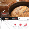 A digital kitchen meat thermometer with a folding probe is shown measuring the internal temperature of a loaf of bread.