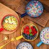 A collection of hand-painted ceramic salad bowls and a wooden board filled with colorful ingredients.