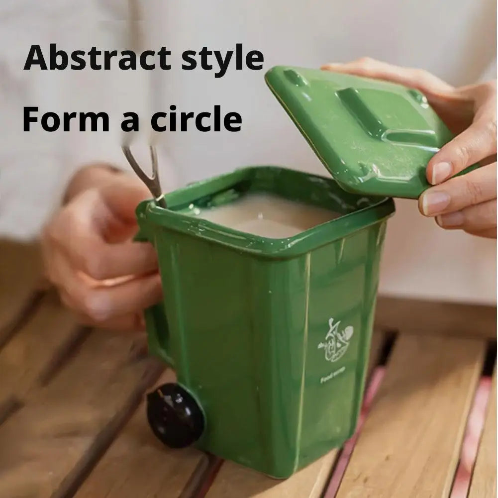 A hand is forming a circle with a green novelty trash can designed like a coffee mug.