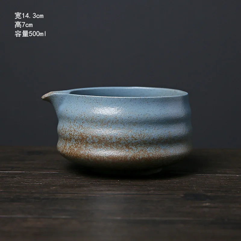 A ceramic matcha bowl with a slightly irregular shape and speckled blue-green glaze sitting on a dark wooden surface.