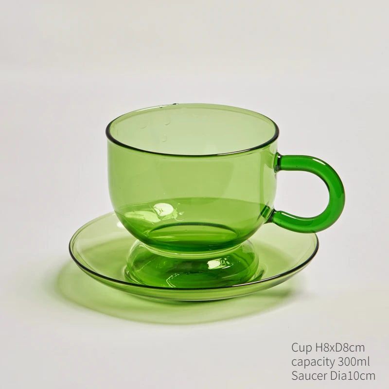 A green glass teacup and mug set with a matching saucer, shown against a white background.