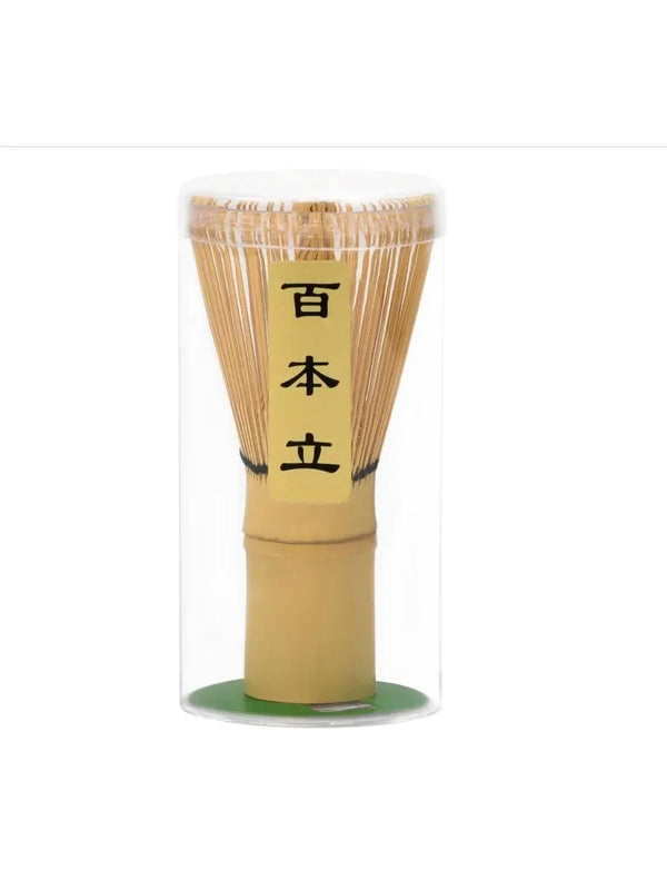 A tall glass container holding a bundle of bamboo matcha whisks with Japanese characters written on the top section.