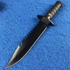 A black multi-function fixed blade tactical knife with a serrated blade and textured handle resting on a blue fabric backgrou