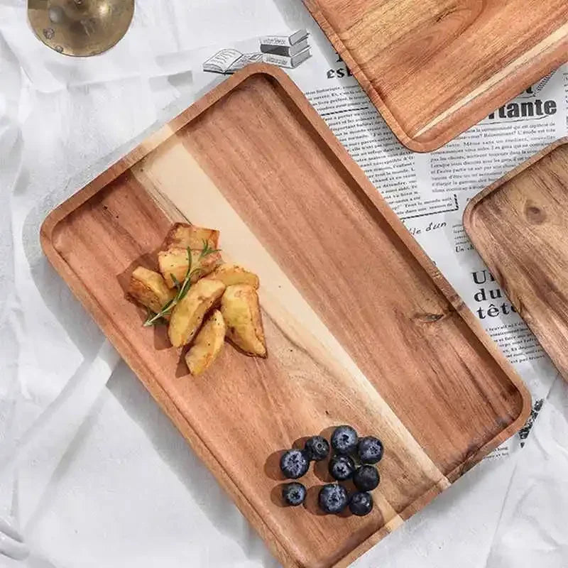 A wooden serving tray holds roasted potato wedges and blueberries on a white cloth.