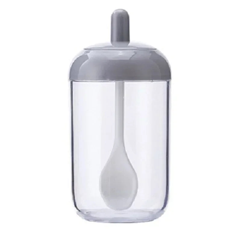 Frasco de condimentos con múltiples aberturas de vidrio transparente y una cuchara blanca dentro