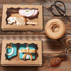 Two decorative kraft paper candy boxes for gifts, one pink and one teal, with natural elements like leaves and twine.