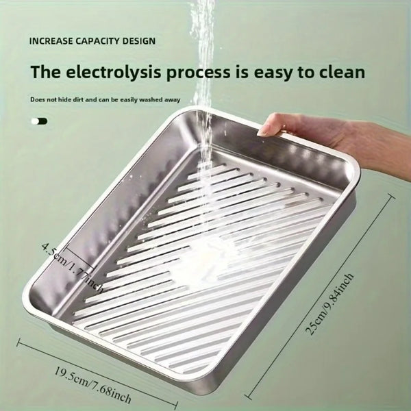 A stainless steel baking tray is shown being rinsed under water, demonstrating its easy-to-clean design.