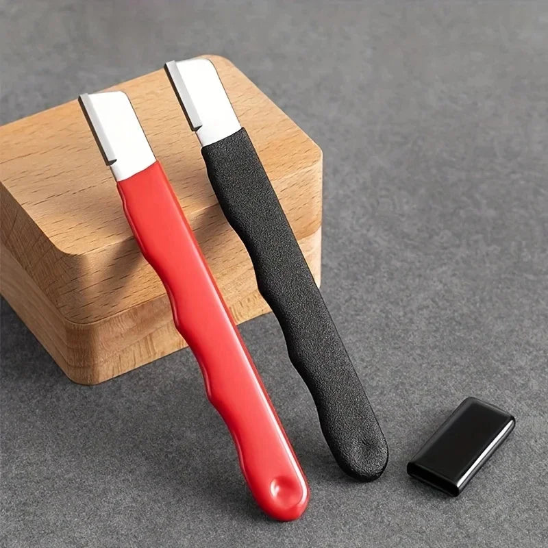 A red and black ceramic knife sharpening tool resting on a wooden block with a small knife blade beside it.