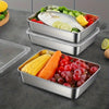 Stackable stainless steel food storage containers filled with fresh vegetables like corn, tomatoes, and lemon slices.