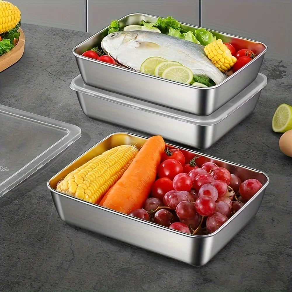 Stackable stainless steel food storage containers filled with fresh vegetables like corn, tomatoes, and lemon slices.