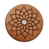 A round wooden bread scoring tool with an intricate, star-like pattern carved into the surface.