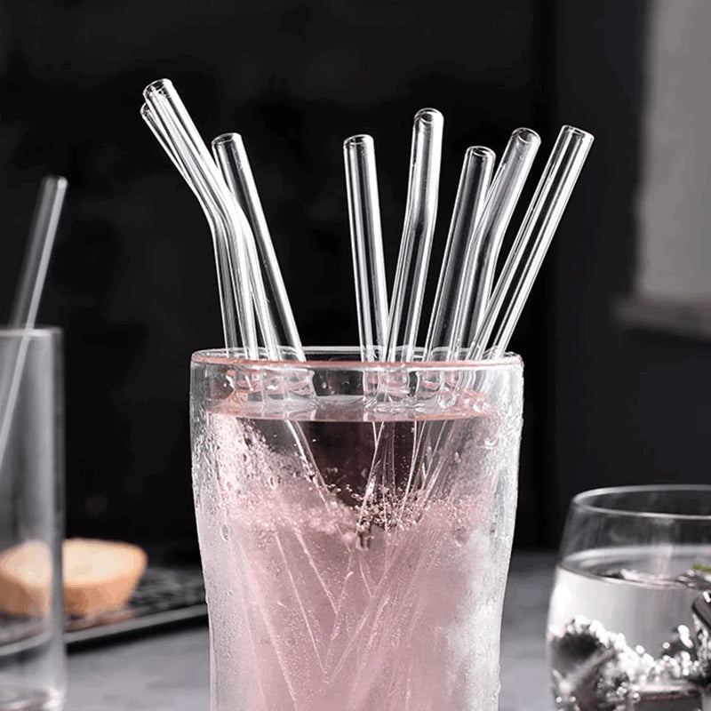 Clear glass drinking straws submerged in a pink liquid inside a glass