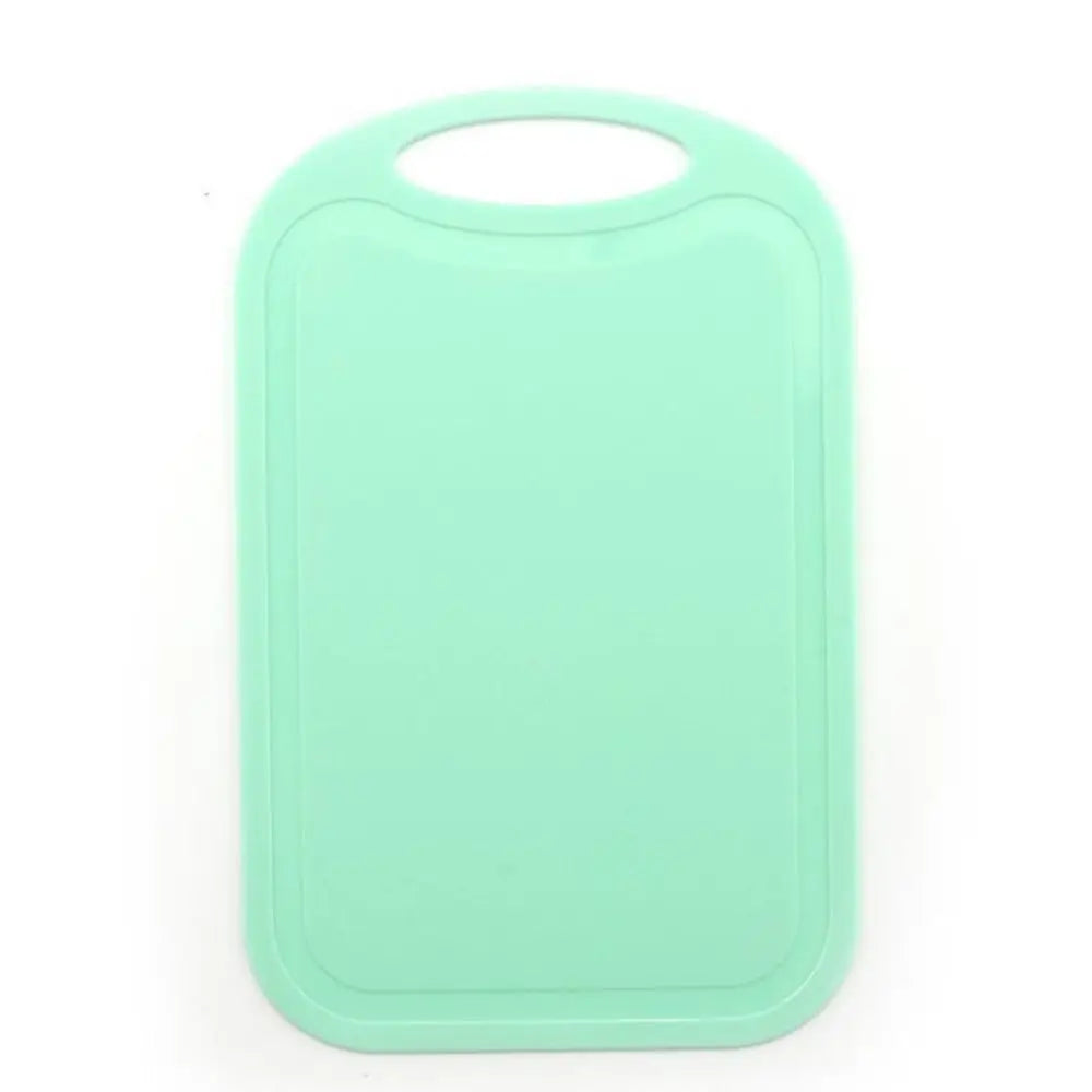A light mint green non-slip plastic cutting board with a hanging handle.