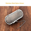 A stainless steel spice infuser with a mesh filter attached to a chain, resting on a wooden surface.