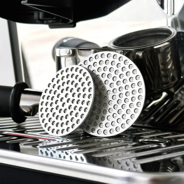 Zwei wiederverwendbare Metall-Espresso-Puck-Siebe auf einem silbernen Tablett.