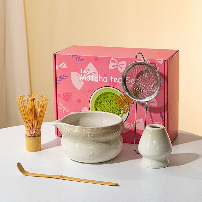 A pink box containing a Japanese matcha tea set with a ceramic bowl and bamboo whisk, displayed on a white surface.