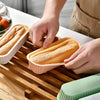 Hands are placing a silicone mini loaf baking pan into a wooden cutting board.