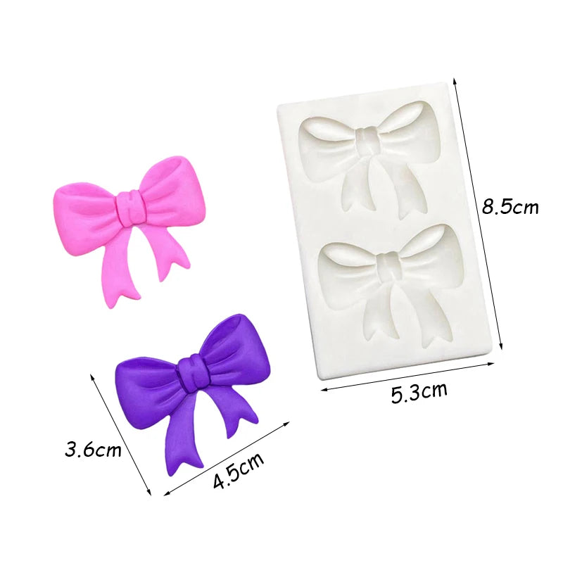 Two silicone baking molds shaped like bows in pink and purple on a white background.