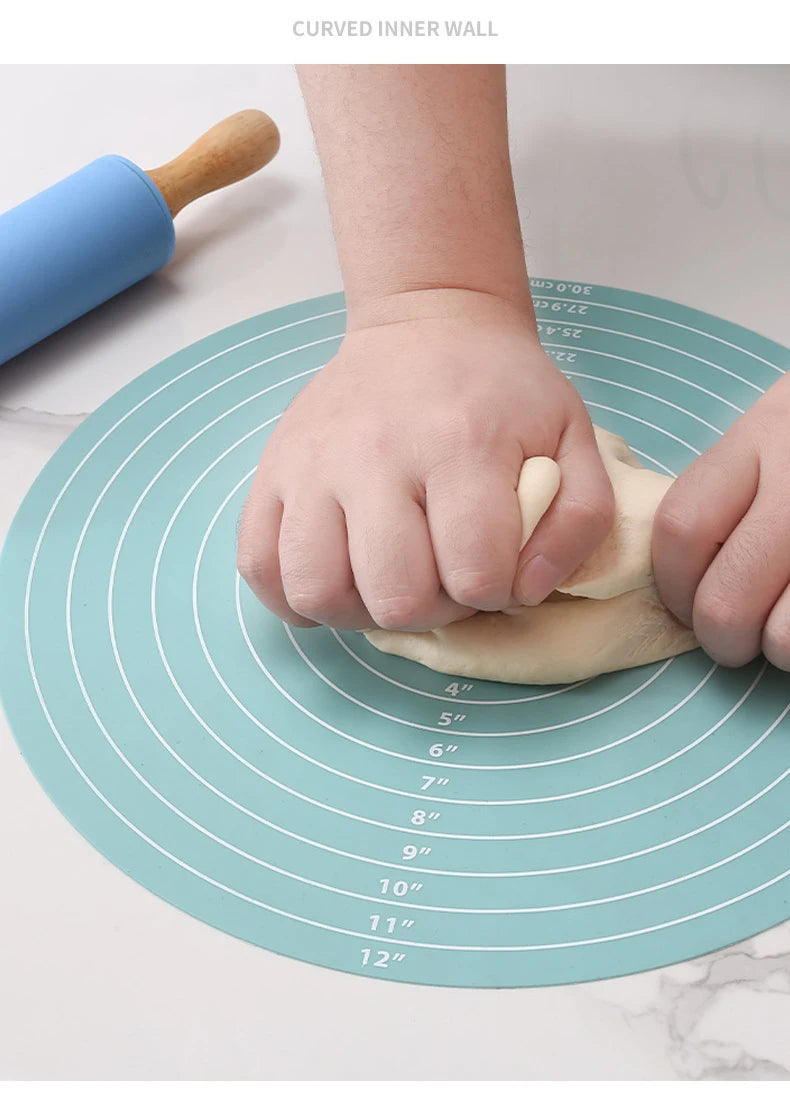 A hand is using a silicone cake turntable baking mat with a wooden tool to rotate a piece of dough.