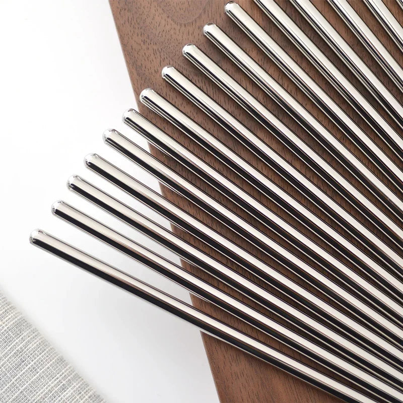 A close-up view of a set of modern stainless steel chopsticks arranged diagonally on a wooden surface.