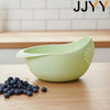 A light green multi-use kitchen drainer colander set resting on a wooden surface with blueberries nearby.