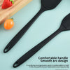 A black silicone kitchen spatula is shown next to fresh strawberries and a tomato on a light blue background.