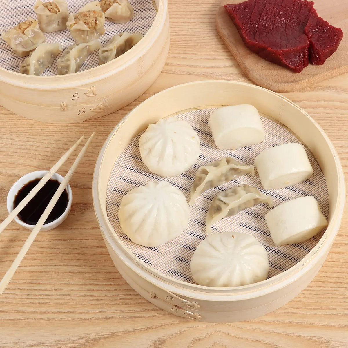 A bamboo steamer basket filled with various dumplings and a piece of red meat on a wooden surface.