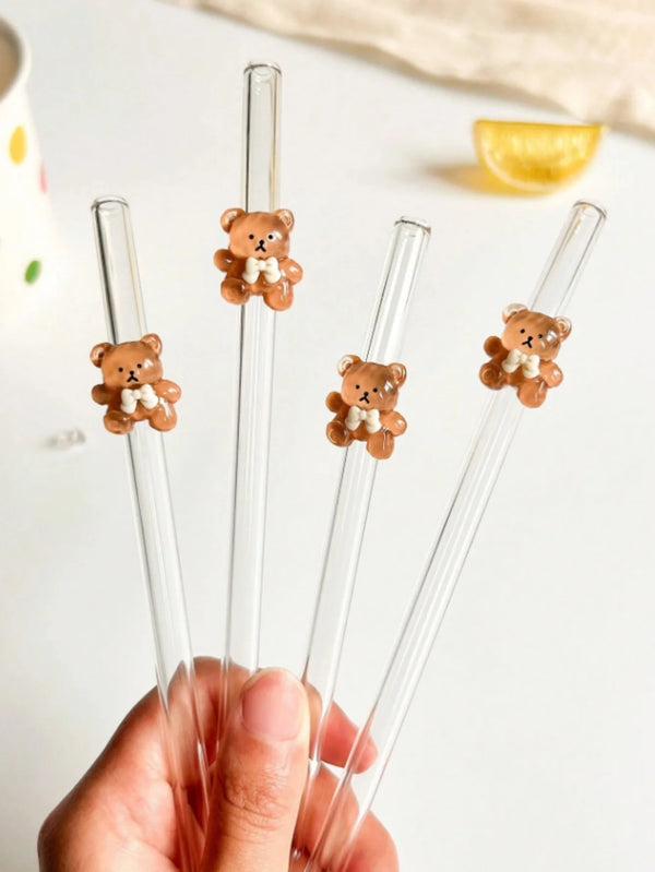 Eine Hand hält ein Set wiederverwendbare Glasstrohhalme mit kleinen Teddybär-Anhängern.