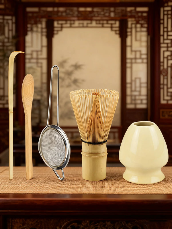 A set of bamboo and metal tools for matcha tea preparation, including a whisk and a ceramic bowl.