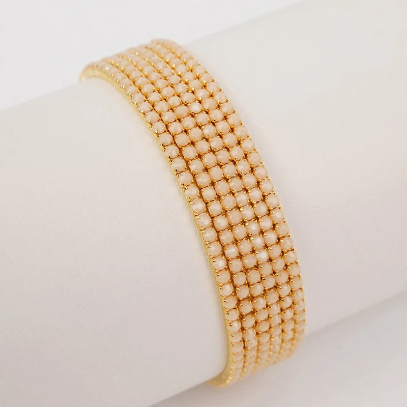 A stack of gold-toned acrylic elastic bracelets worn on a wrist.