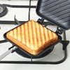 A grilled sandwich is placed in a non-stick pan on a black stovetop grill.
