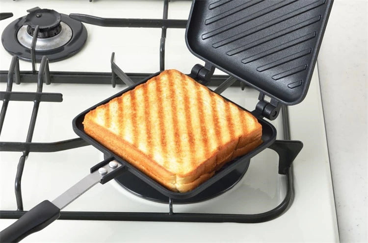 A grilled sandwich is placed in a non-stick pan on a black stovetop grill.