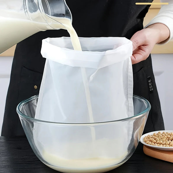 A hand pours white liquid into a clear mesh strainer placed over a glass bowl.