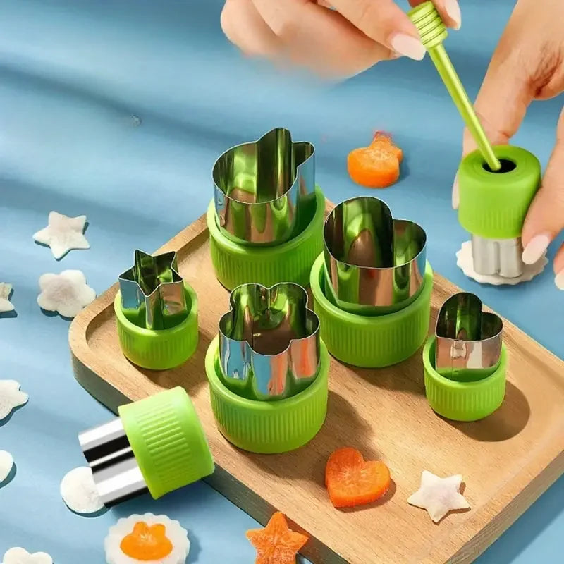 A set of 12 stainless steel vegetable and fruit molds in bright green and silver are displayed on a wooden board.