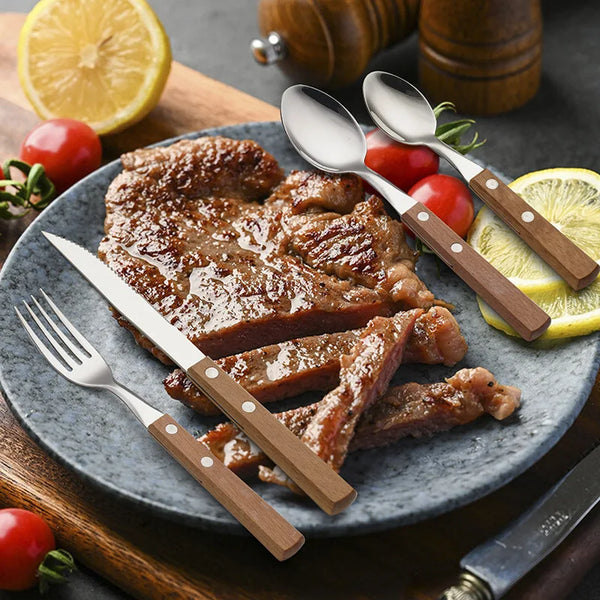 Edelstahl-Reiseutensil-Set mit Fleischgericht, frischen Tomaten und Zitronenscheiben auf dunklem Teller