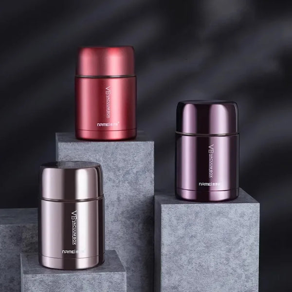 Two stainless steel food jars in rose gold and dark pink are displayed on gray cubes.