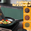 A hand is grinding spices in a black electric grinder over a frying pan.