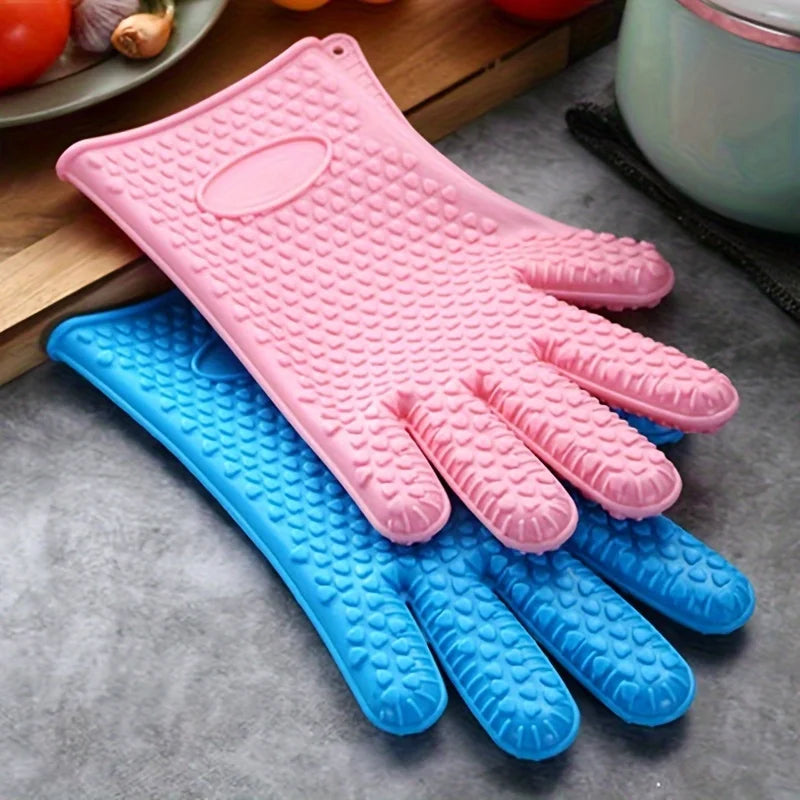 A set of pink and blue silicone heat resistant kitchen and BBQ gloves displayed on a gray surface.