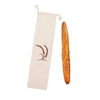 A beige linen bread bag with a drawstring tied at the top and a loaf of brown bread hanging inside.
