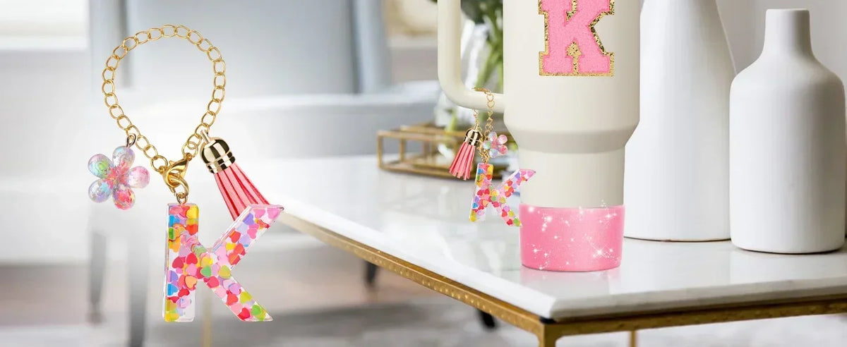 A set of silicone straw covers in pink and gold designs resting on a white table.