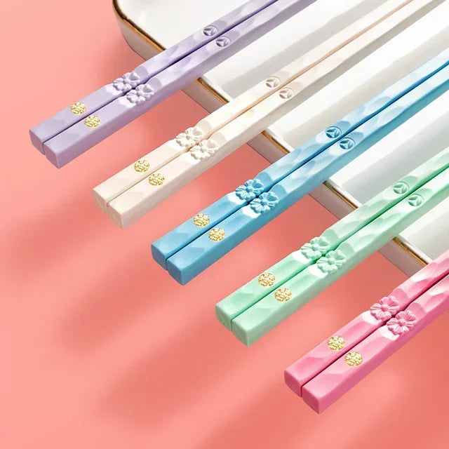 A set of reusable multi-color chopsticks in lavender, beige, blue, and mint green are displayed on a white surface.