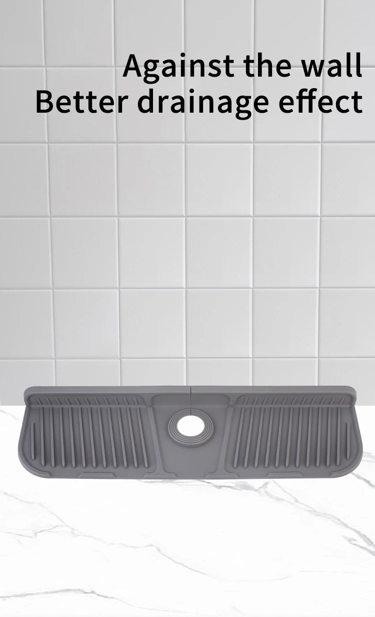 A gray silicone sink splash guard mat with ridges and a central hole, shown against a white tiled background.